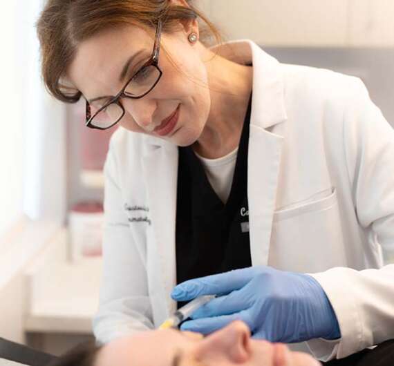 Dr. Carla Gustovich performing an injection in clinic at magnolia dermatology