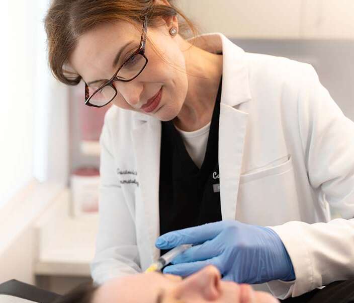 Dr. Carla Gustovich performing an injection in clinic at magnolia dermatology